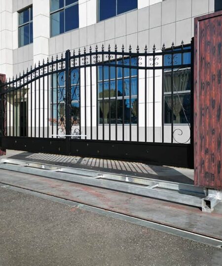 Metallic driveway gate with wooden panels in front of a building