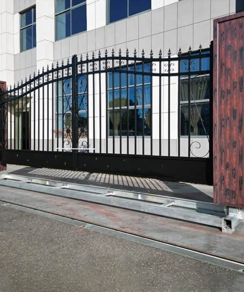 Metallic driveway gate with wooden panels in front of a building