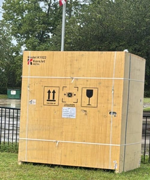 Wooden shipping container with handling symbols and KoreJetMetal logo.